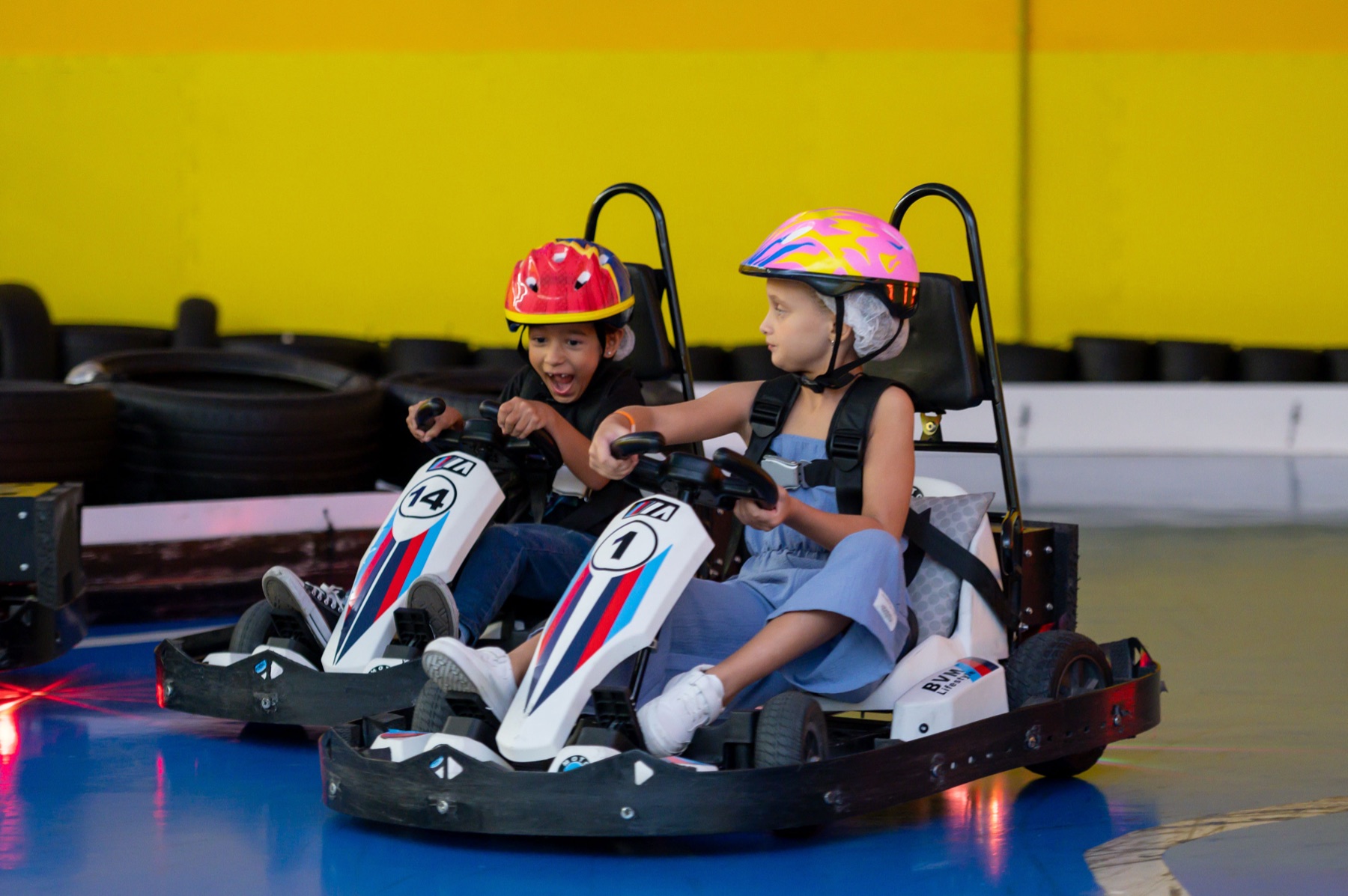 Duas crianças gritando de alegria a bordo de um kart elétrico