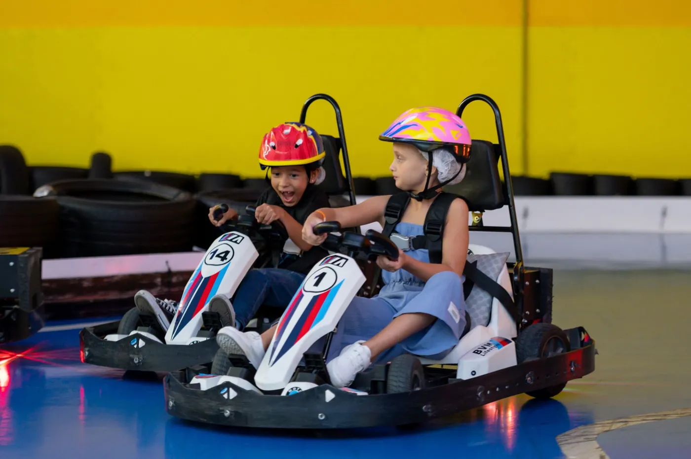 Duas crianças gritando de alegria a bordo de um kart elétrico