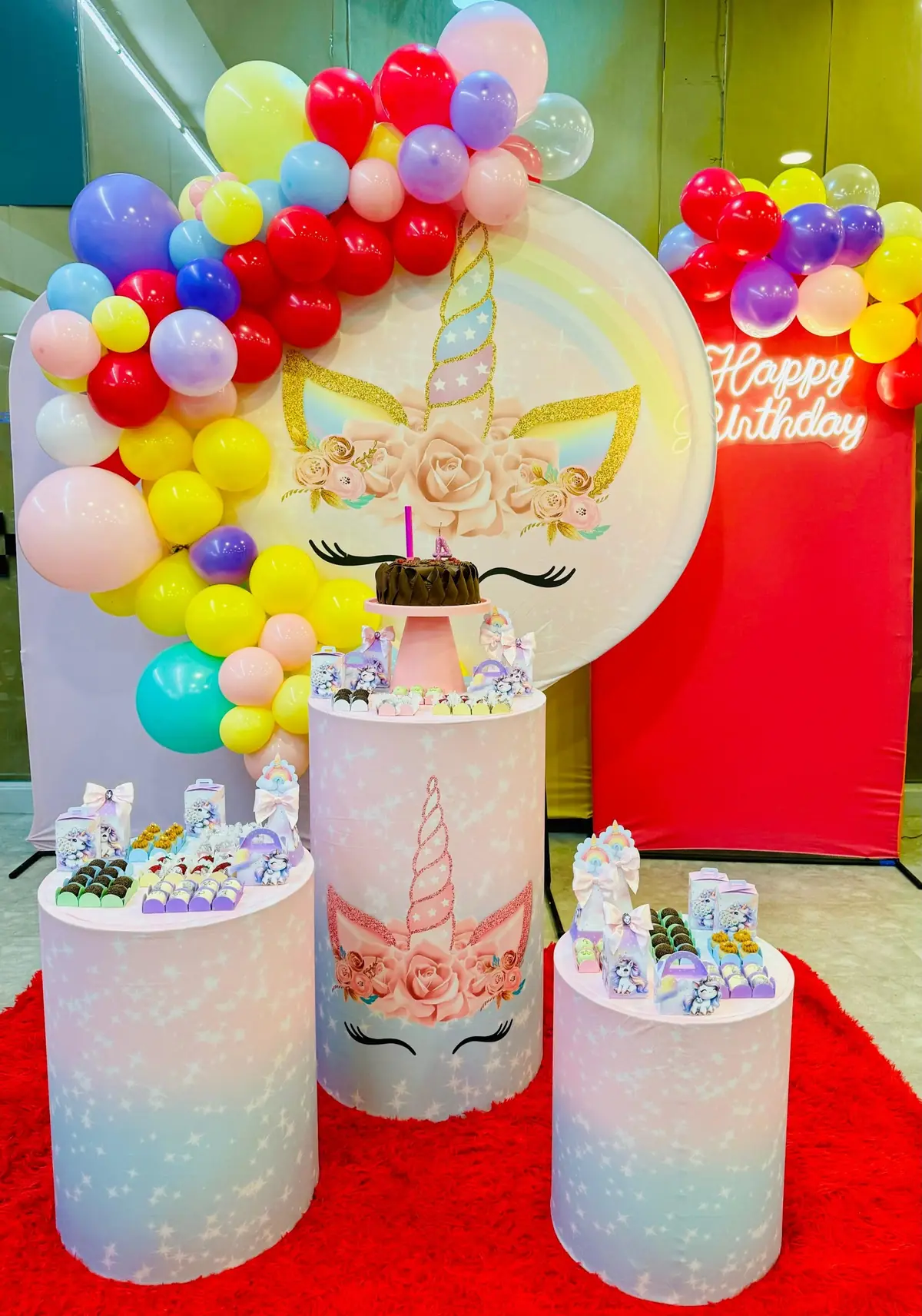 Mesa do parabéns com decoração de unicórnio, balões coloridos e painel Happy Birthday